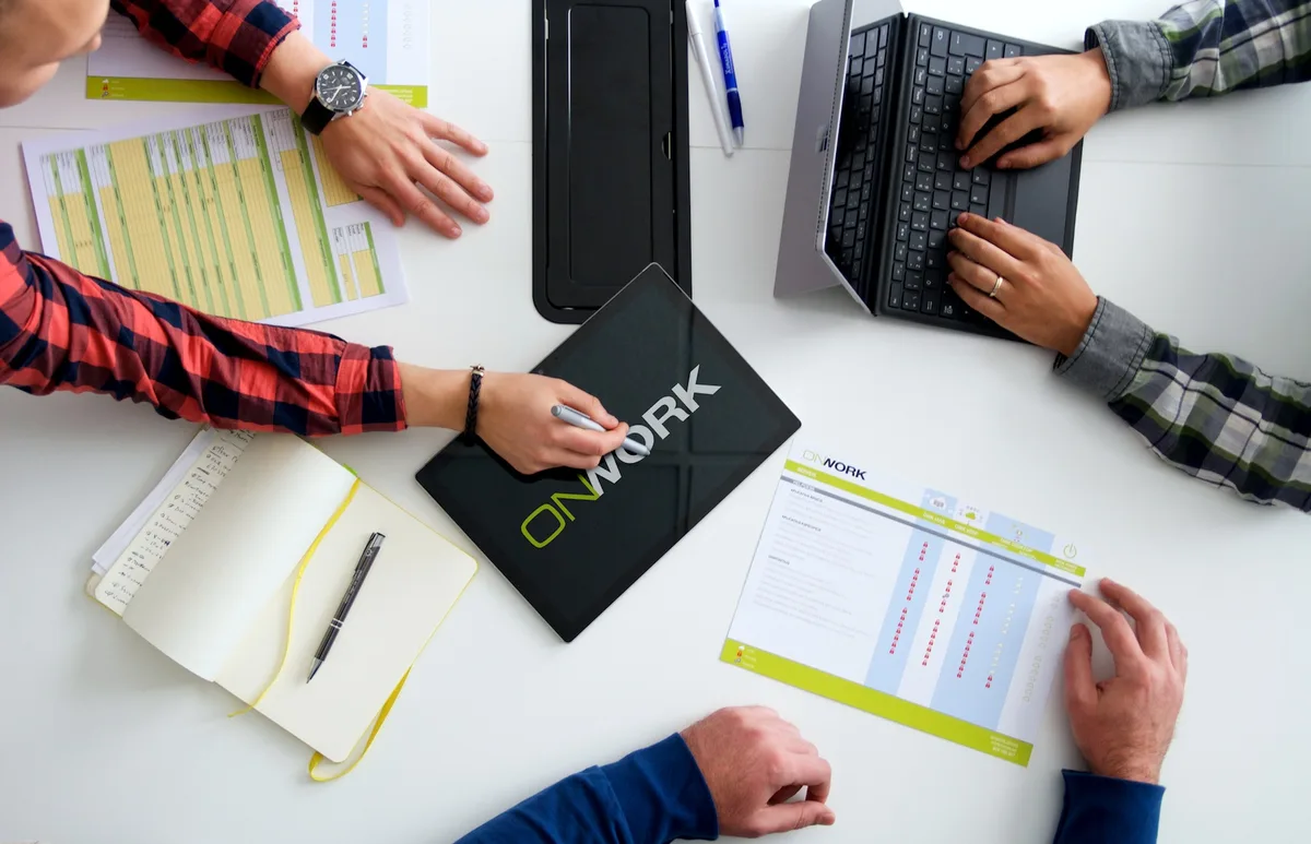 Manos del equipo sobre documentación de OnWork